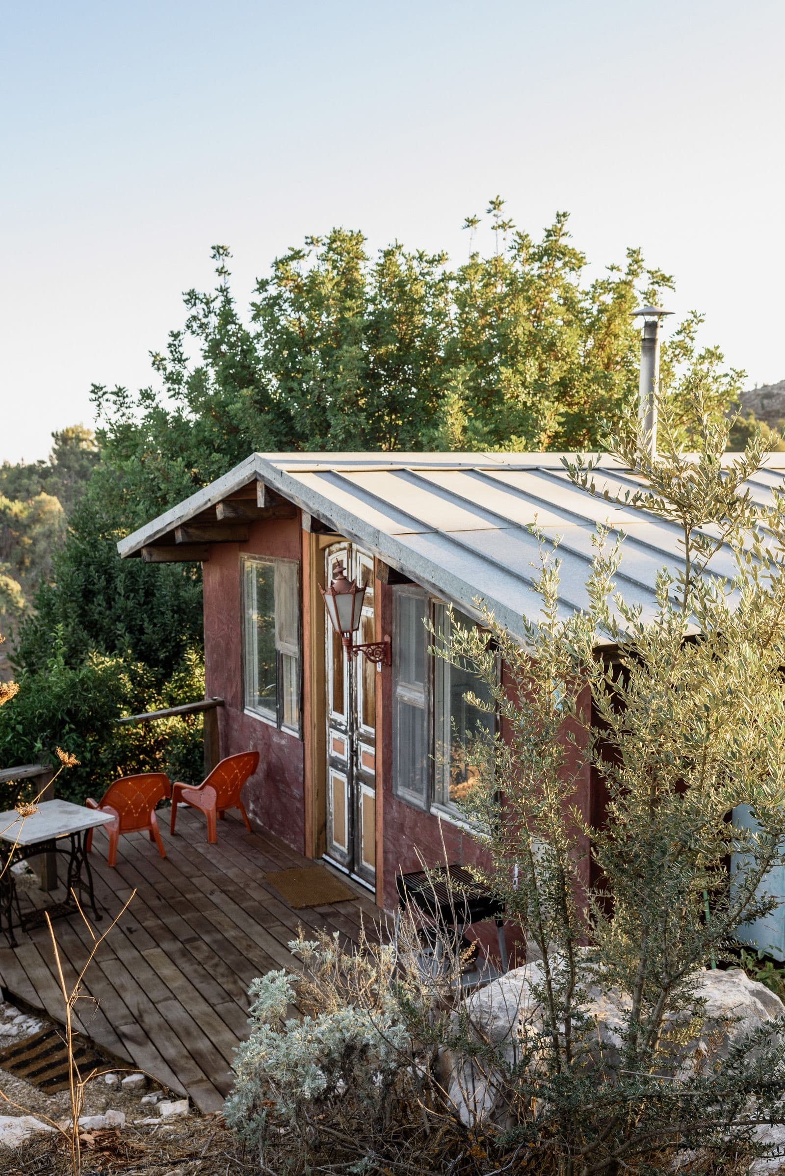 The homestay cottage among trees with a small garden table