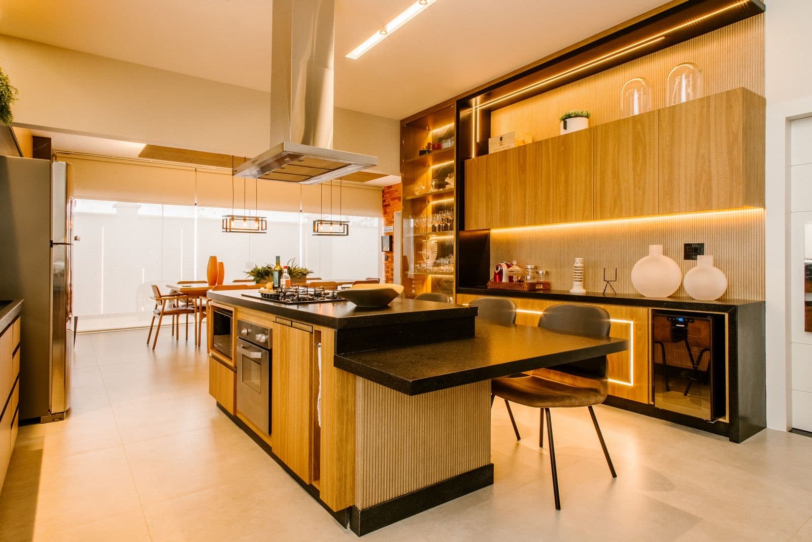 A warm wood kitchen with a black stone island and pendant lights